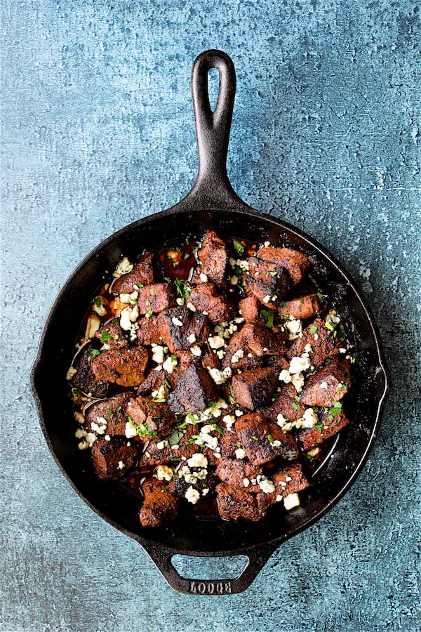 Buttery Blackened Steak Bites with Gorgonzola - Overhead shot of steak bites sprinkled with Gorgonzola cheese in cast iron skillet