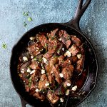 Buttery Blackened Steak Bites with Gorgonzola in cast iron skillet with serving spoon.