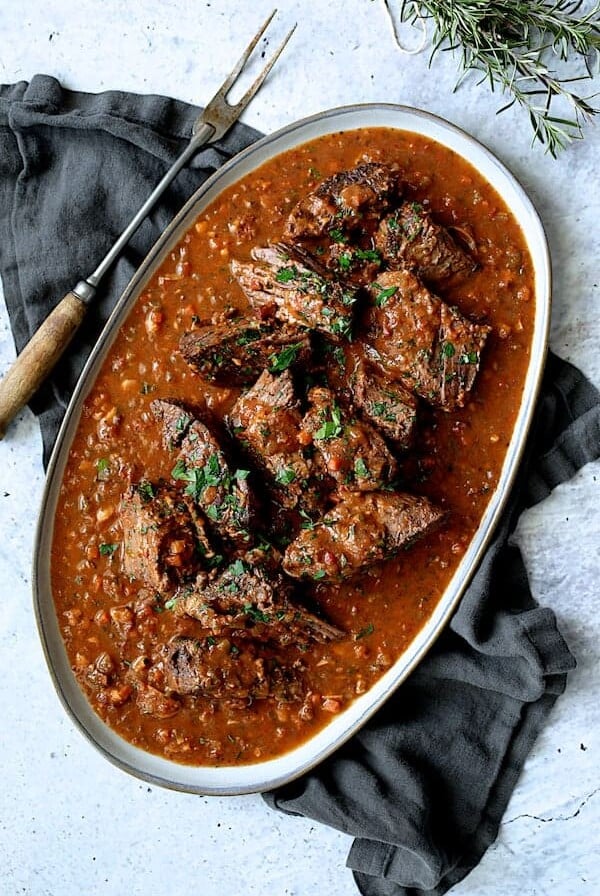 Italian Pot Roast (Straccato) on gray-rimmed oval platter garnished with fresh rosemary.