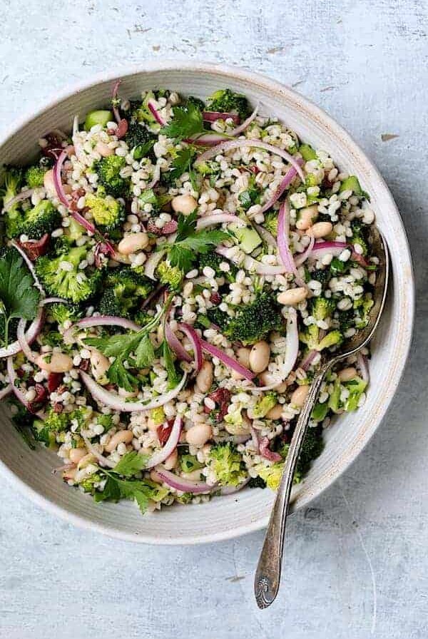 Lemony Broccoli, Barley and Bean Salad in white serving bowl with serving spoon.