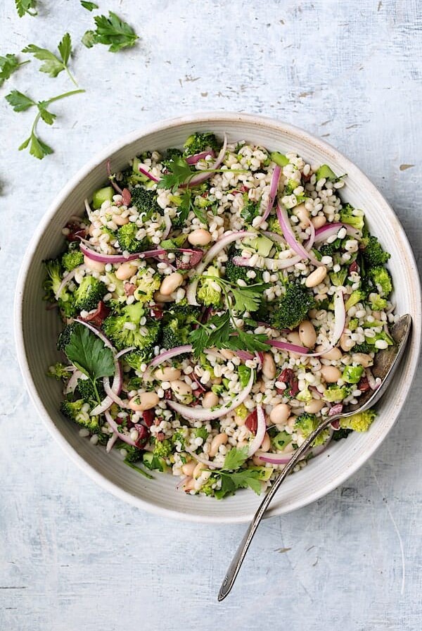 Lemony Broccoli, Barley and Bean Salad in white serving bowl with serving spoon.