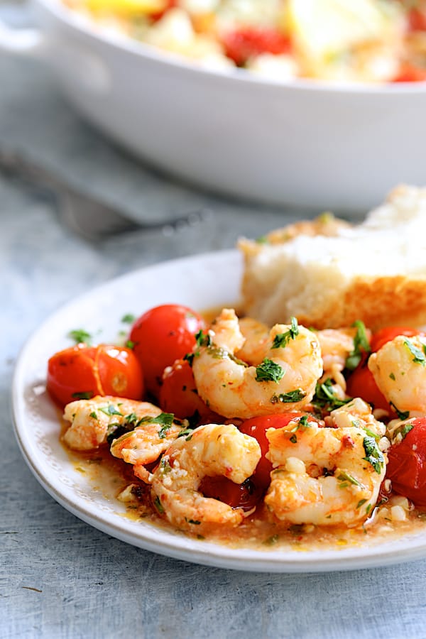 Photo of one serving of Spicy Baked Shrimp with Tomatoes and Feta Cheese on white plate with bread.