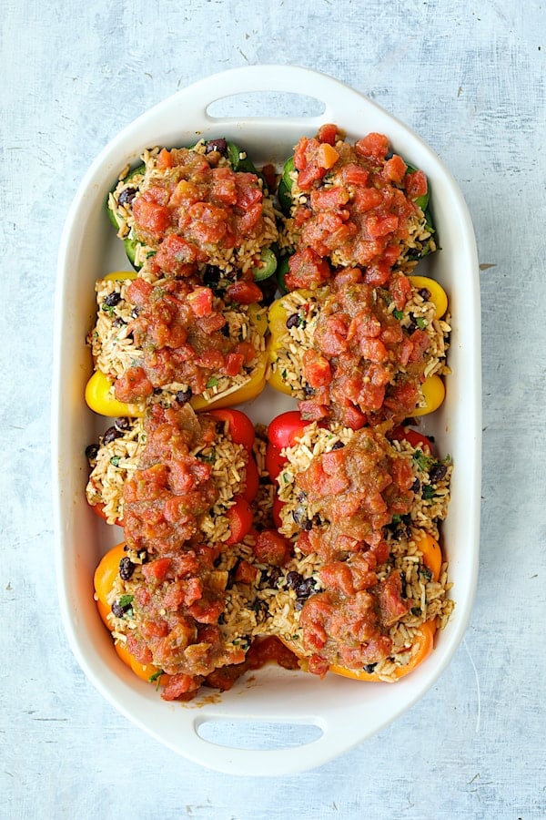 Photo of assembled peppers in white baking dish with salsa added.