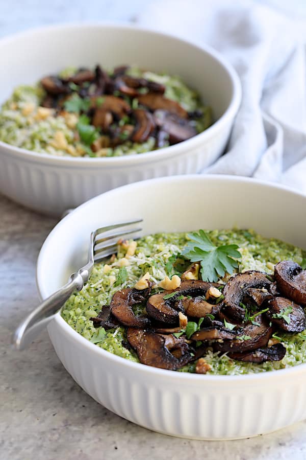 Photo of two bowls of Oven Risotto with Kale Pesto and Roasted Mushrooms in white bowls.