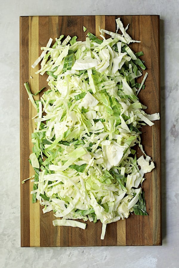 Photo of sliced cabbage on wood cutting board.