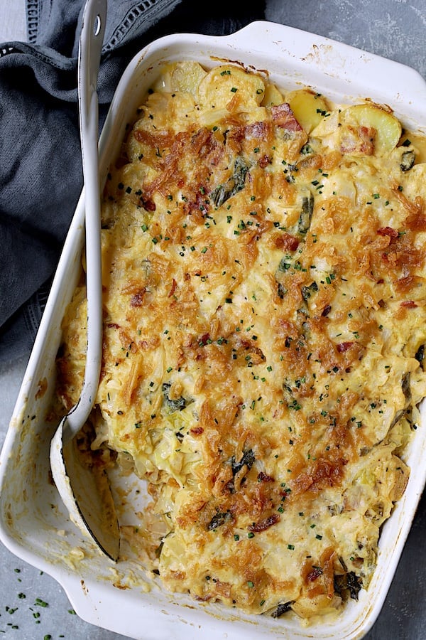 Potato and Cabbage Casserole with Cheddar and Bacon with white serving spoon with some spooned out.