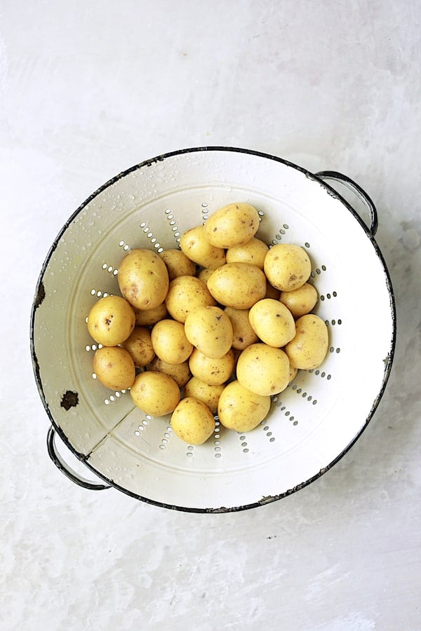 Photo of small Yukon gold potatoes in white vintage colander.