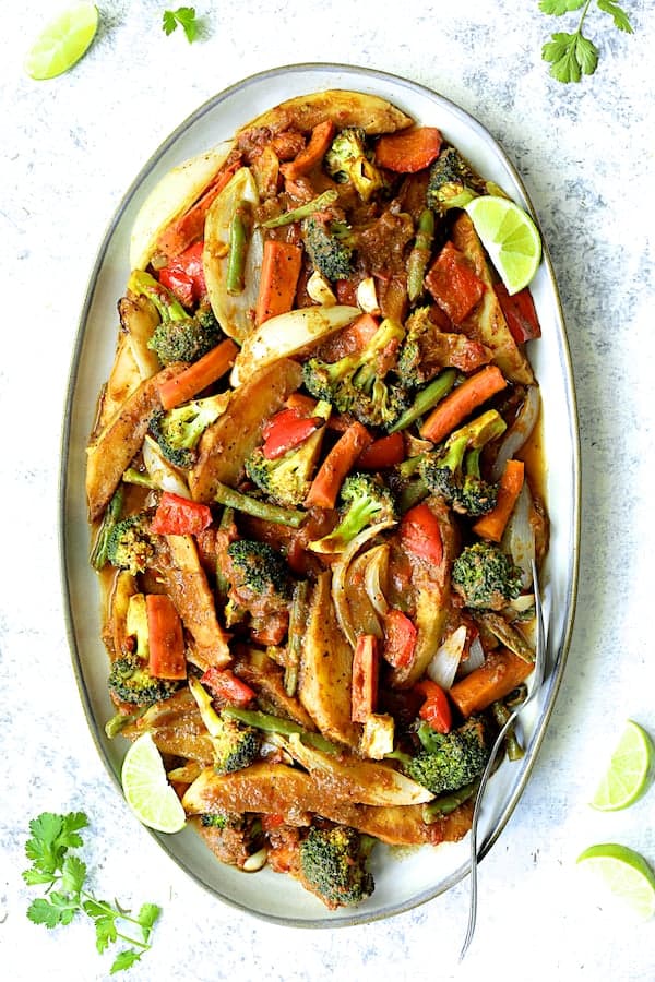 Photo of Curried Roast Vegetables on platter garnished with lime wedges and cilantro.