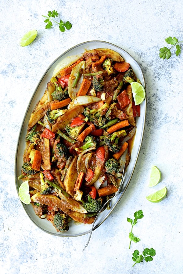 Photo of Curried Roast Vegetables on oval platter garnished with lime wedges and cilantro sprigs.