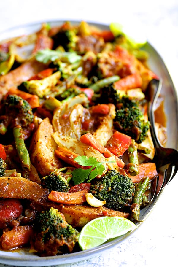 Close-up photo of Curried Roast Vegetables on oval platter with serving fork.