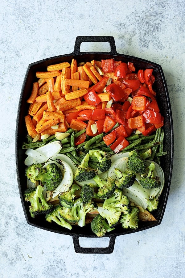 Photo of partially roasted vegetables on cast iron pan with broccoli added.