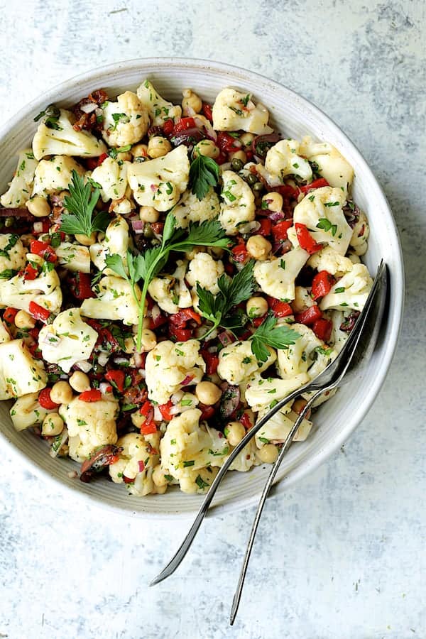 Photo of Sicilian Cauliflower Salad in white serving bowl with serving utensils.