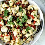 Sicilian Cauliflower Salad in white serving bowl with serving utensils.