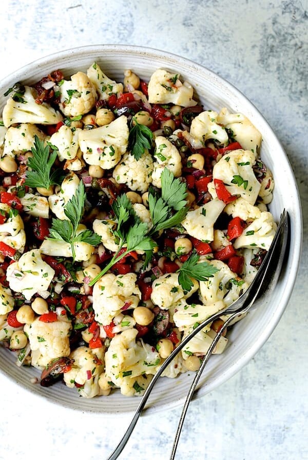 Sicilian Cauliflower Salad in white serving bowl with serving utensils.