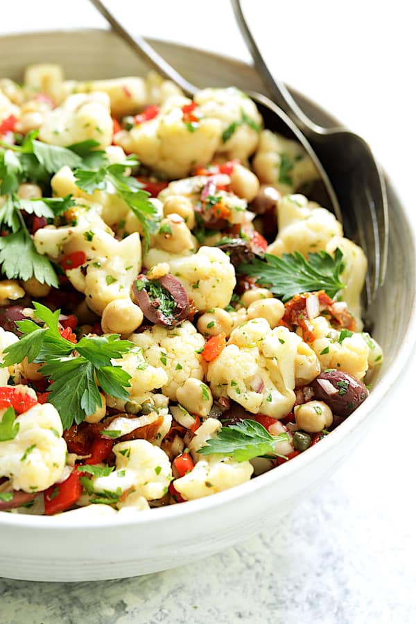 Photo of Sicilian Cauliflower Salad in white serving bowl garnished with parsley sprigs.