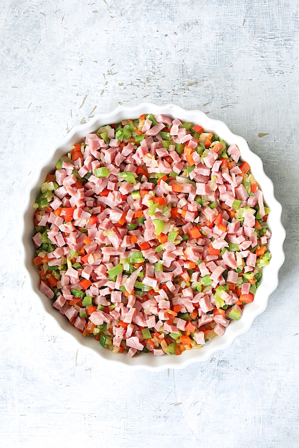 Photo of peppers and ham in round white baking dish before custard is added.
