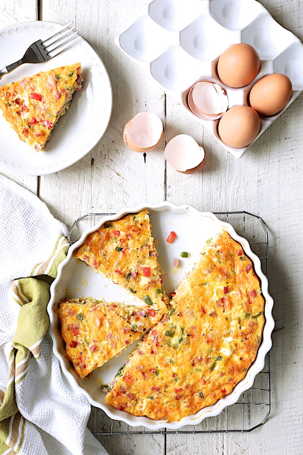 Photo of Spicy Baked Denver Omelet on cooling rack cut into pieces with eggs and eggshells nearby.