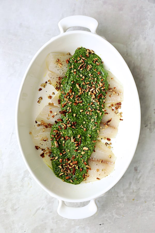 Photo of uncooked tilapia with pesto over the top.