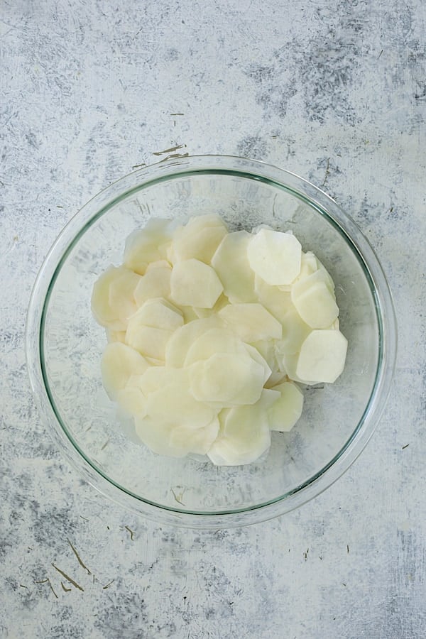 Photo of potato slices in glass bowl.