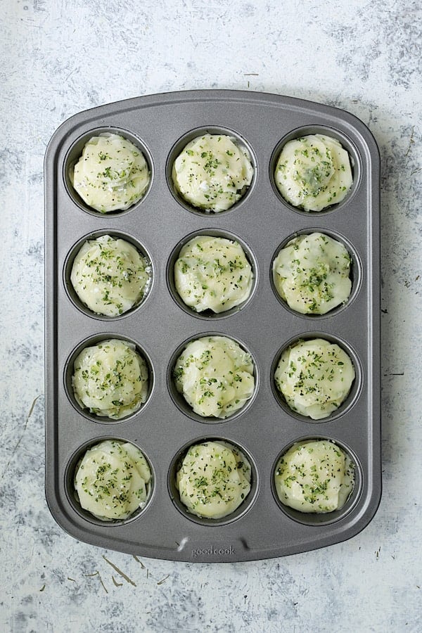 Photo of potato slices stacked into 12-cup muffin pan.
