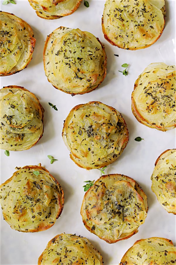 Overhead close-up photo of Garlic Herb Muffin Pan Potato Galettes on white platter.