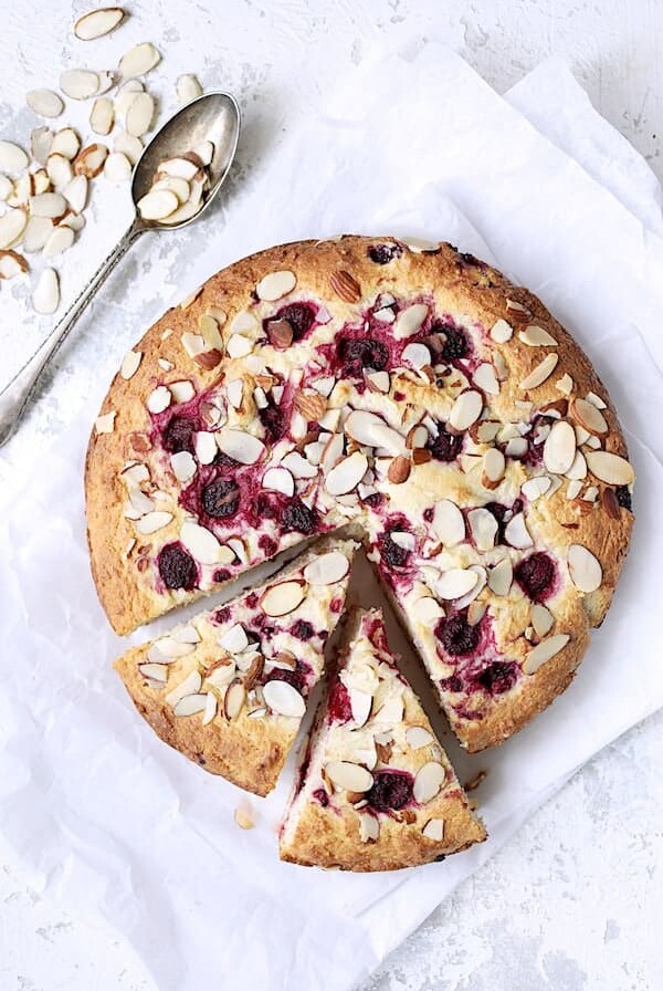 Raspberry Ricotta Cake with Almonds with two wedges cut from the whole cake.