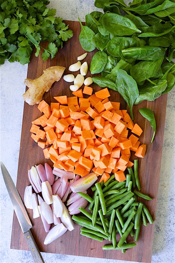 Photo of fresh ingredients for Vegan Thai Sweet Potato Curry on wood cutting board.