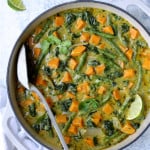 Vegan Thai Green Sweet Potato Curry in white enamel cast iron skillet garnished with cilantro and lime wedges.