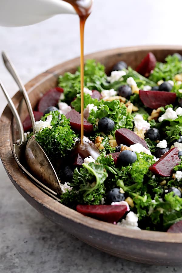 Photo of Massaged Kale, Beet and Blueberry Salad being drizzled with Honey - Balsamic Dressing.