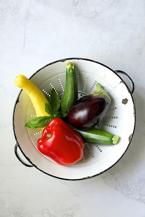 Photo of vegetables for tart in white colander.