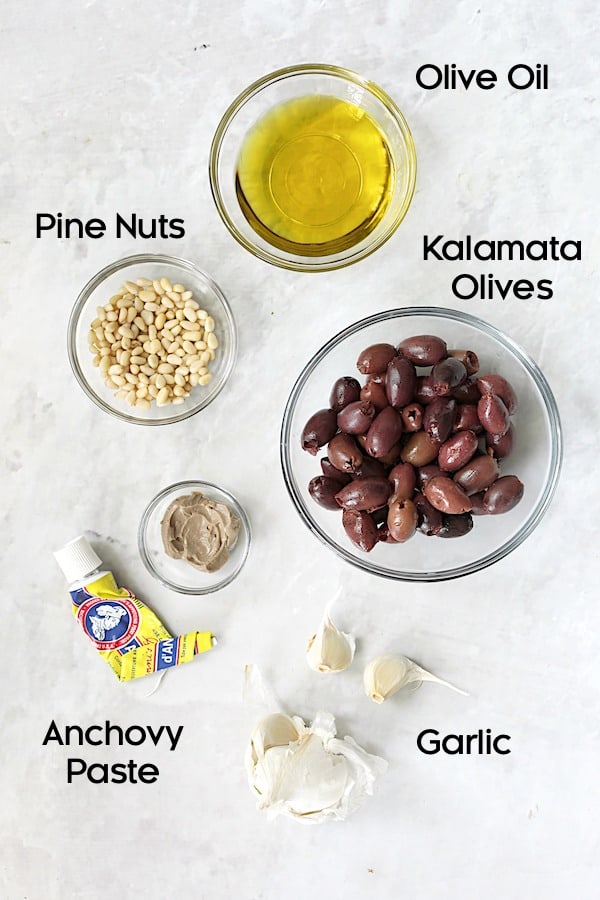 Photo of ingredients for tapenade in glass bowls.