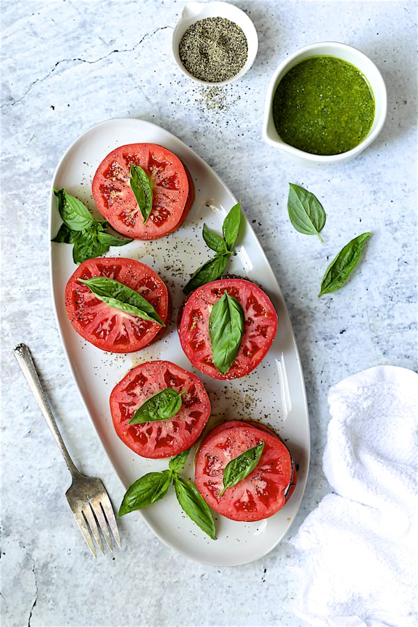 Photo of tomato stacks on white oval platter ready to be dressed and served.