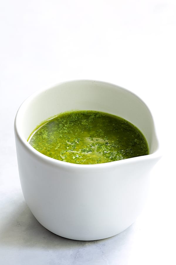 Photo of basil pesto dressing in small white pitcher.