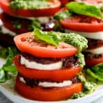 Stacked Tomato Salad with Tapenade and Basil Pesto Dressing - Close-up hero shot on white platter