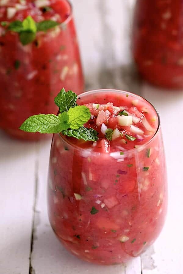 Watermelon Gazpacho with Serrano Chiles and Mint - Hero shot of soup in glasses garnished with fresh mint on white distressed background
