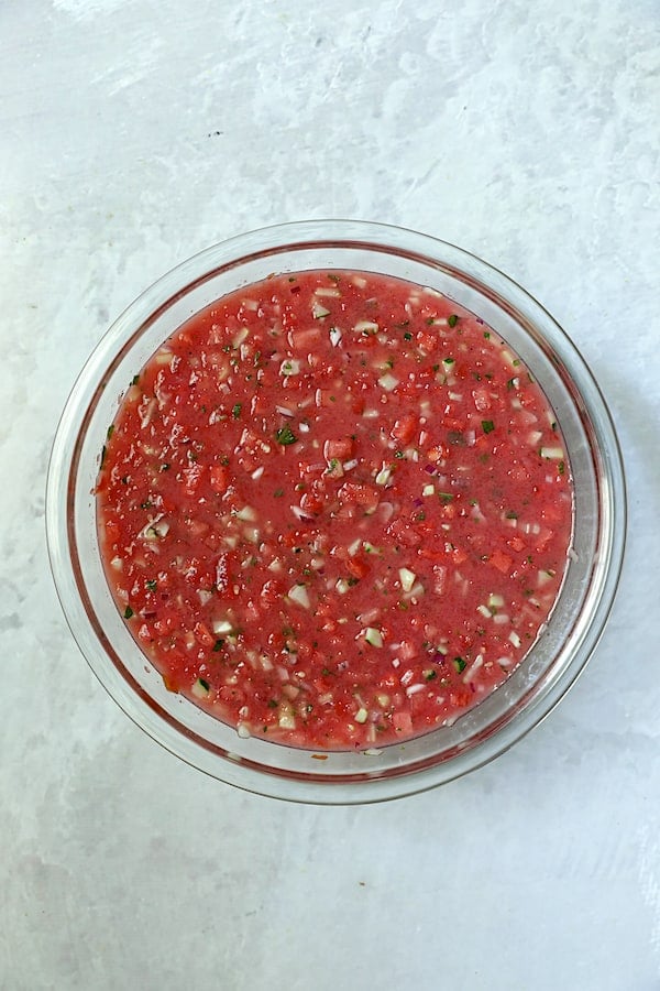 Photo of gazpacho in glass bowl after ingredients are combined.