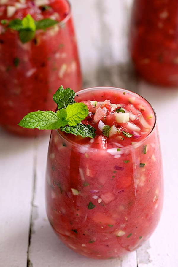 Photo of Watermelon Gazpacho with Serrano Chiles and Mint in glasses garnished with fresh mint on white distressed background.