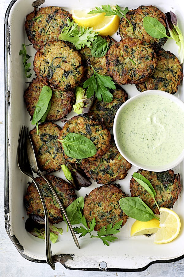 Photo of Zucchini Red Lentil and Spinach Fritters with Cilantro Yogurt Sauce in white pan.