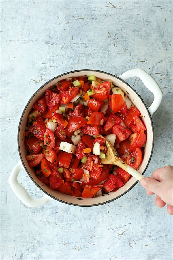 Photo of ingredients for tomato sauce in white Dutch oven before being cooked.