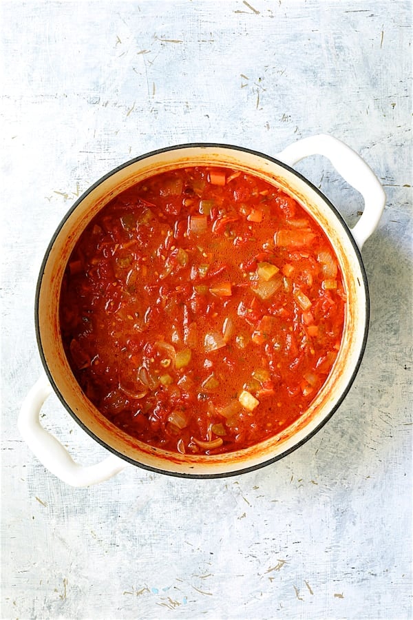 Photo of cooked tomato sauce in white Dutch oven.