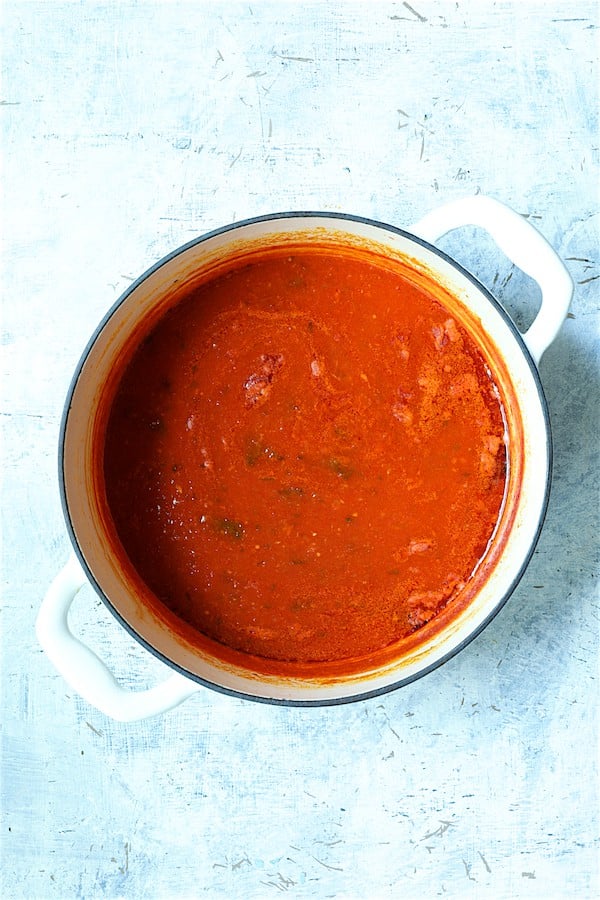 Photo of cooked tomato sauce in white Dutch oven.