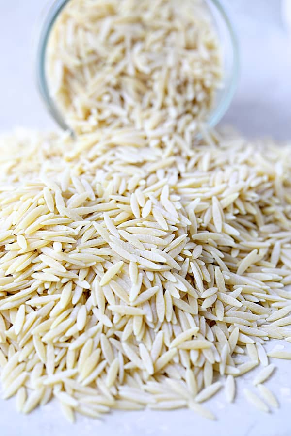 Photo of orzo pasta spilling out of a glass jar.