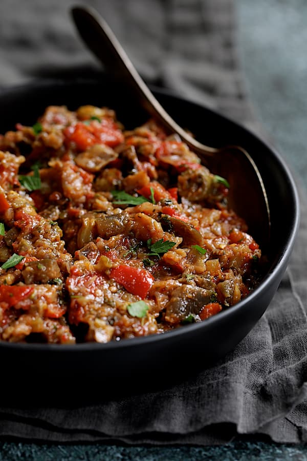 Close-up photo of Moroccan-Spiced Caponata in black serving bowl with spoon.
