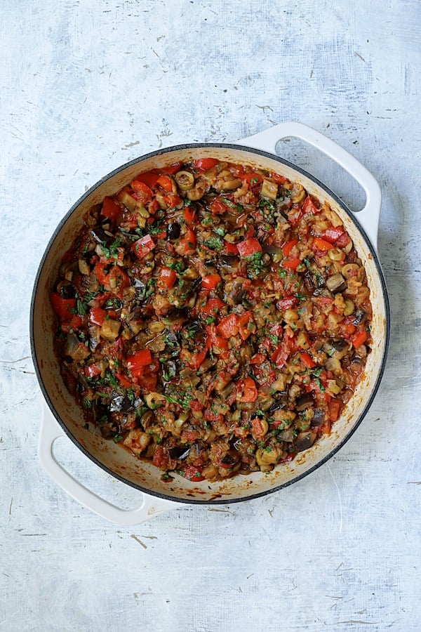 Photo of finished caponata in white cast iron skillet.
