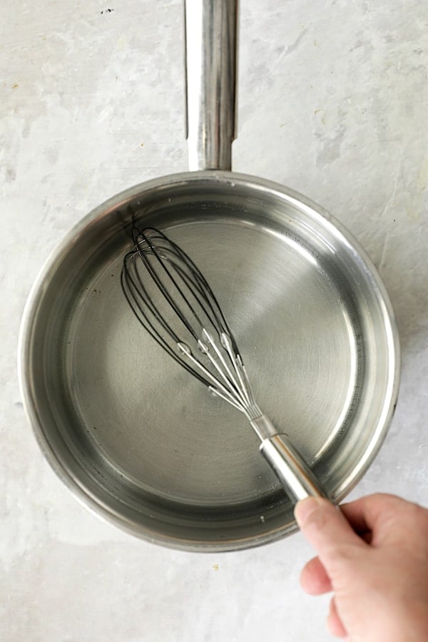 Photo of brine in saucepan being stirred with wire whisk.