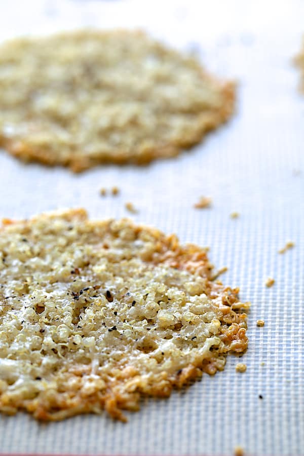 Close-up photo of Quinoa Parmesan Crisps on Silpat-lined baking sheet after being baked.