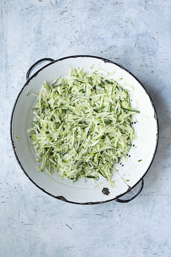 Photo of shredded zucchini in white distressed colander.