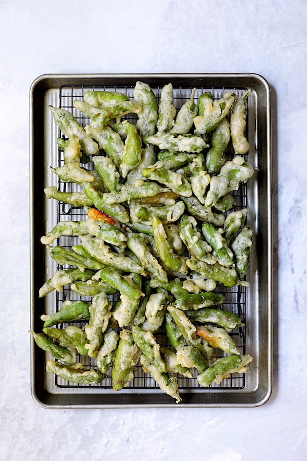 Photo of fried peppers on rack set over rimmed baking sheet.