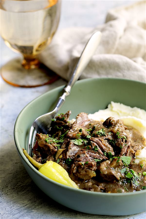 Photo of Mississippi-Style Boneless Short Ribs in green bowl with mashed potatoes garnished with parsley.