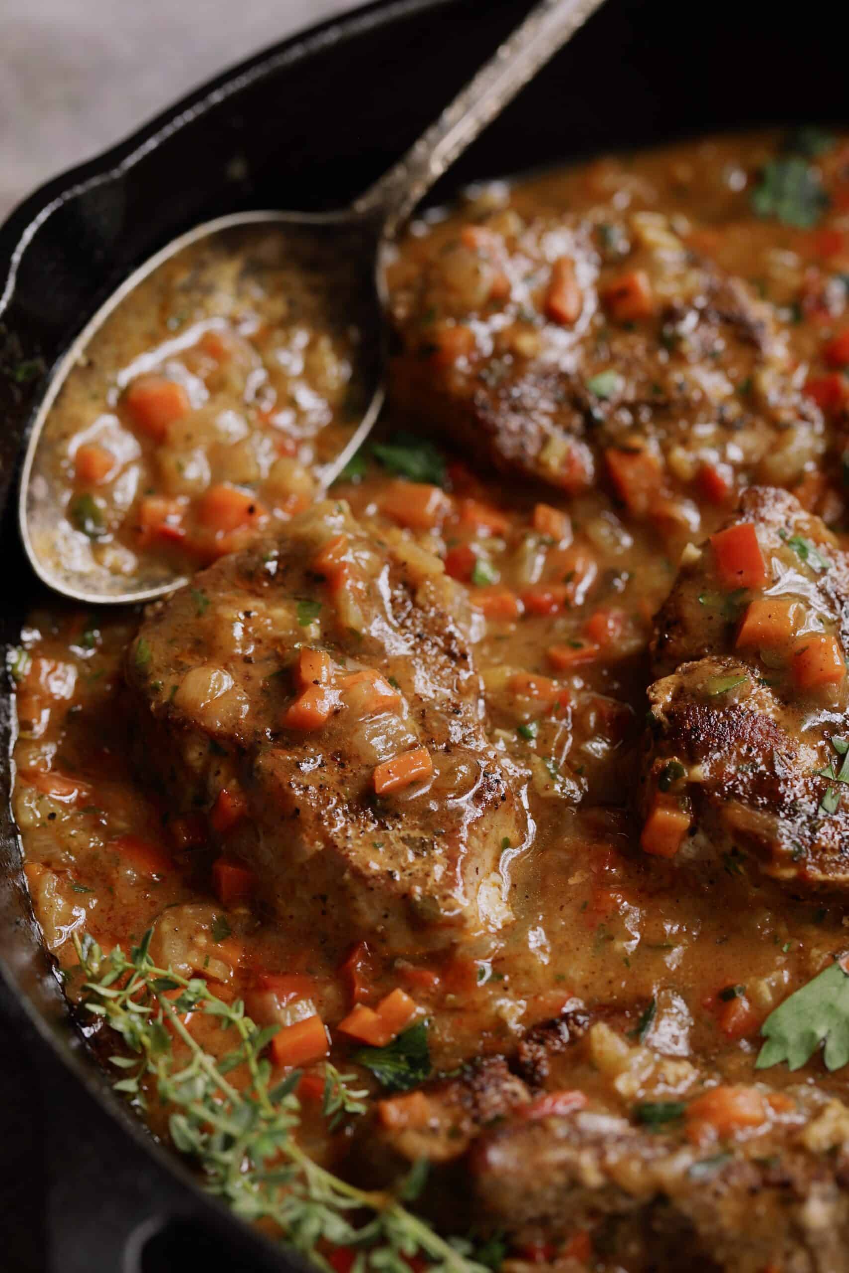 Close-up photo of Cajun-Smothered Pork Medallions in cast iron skillet.